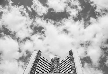 A grey-scale shot of the upper part of a building with cloudy sky in the backgroundの写真素材