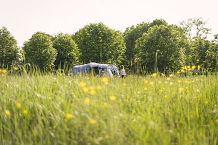 A person making a tent at a camp place surrounded by beautiful greeneryの写真素材