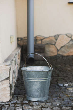 A vertical shot of a metal bucket in the street in front of a buildingの写真素材