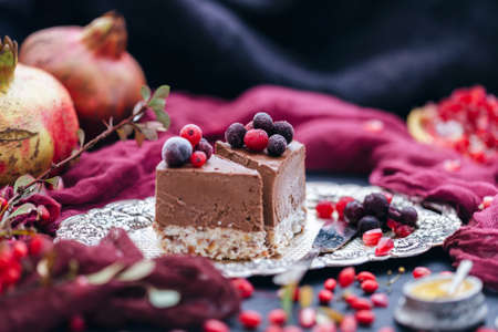 Two pieces of chocolate cakes on a metal plate with berries and fruits scattered around