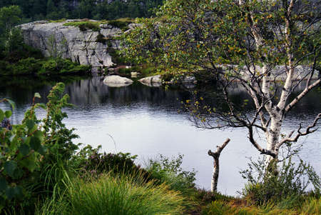 A breathtaking scenery of a lake with the reflection of trees surrounded by rock formations in...