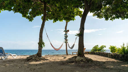 Two hammocks hanging in the trees with a beautiful ocean in the backgroundの写真素材