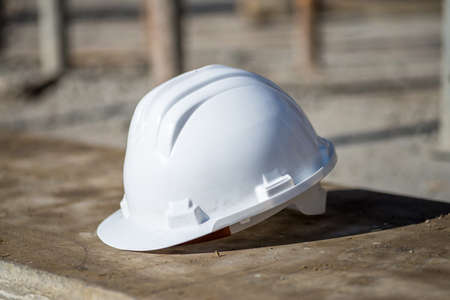 A white construction helmet on the ground under the sunlight with a blurry background