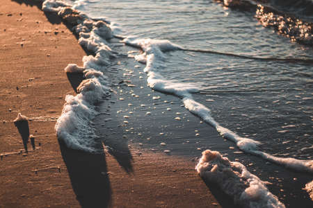 A high angle closeup shot of waves on the shore with sand - perfect for wallpaperの写真素材