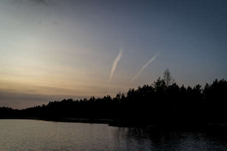 A small lake ahead of a dense forest during the dusk