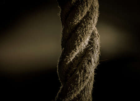 A closeup shot of a thick rope with a dark blurry backgroundの写真素材