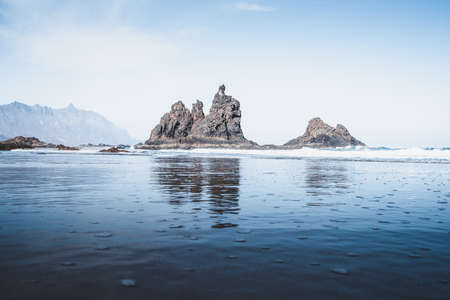 The rock formations in the sea with reflections in the waterの写真素材