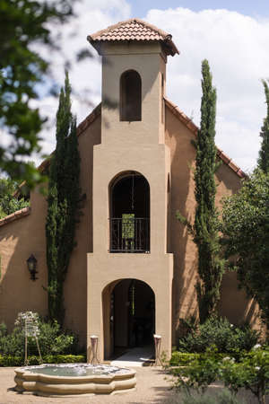 A vertical shot of a beige building with a garden trees