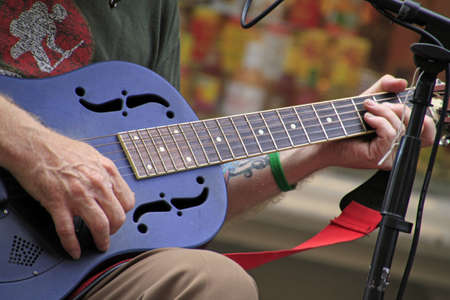 A selective focus shot of a person playing the guitar on the street