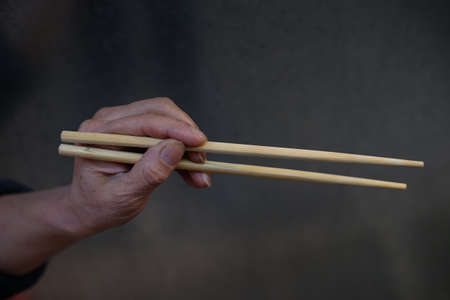 A person holding Chinese wooden chopsticks for eating