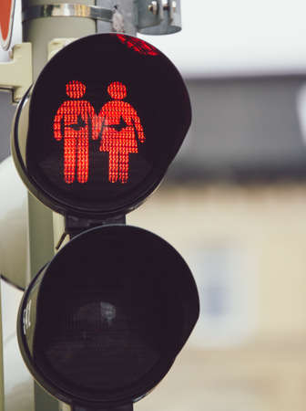 A closeup shot of a traffic light showing a man and a woman holding hands