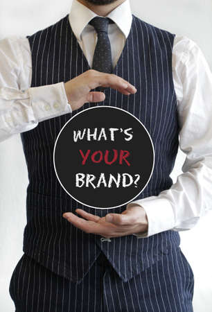 A vertical shot of a businessman presenting a circle with "what's your brand?" written insideの写真素材