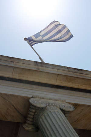 A low angle shot of the flag of Greece on a building