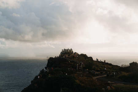 A high angle shot of a modern architectural building at the top of the cliff of the ocean with...