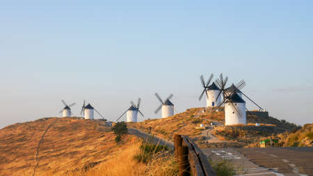 A panoramic shot of beautiful Windmills on a grassy hill in  Consuegra, Spainの写真素材