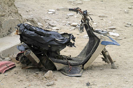 A broken motorcycle put on the sand surrounded by stonesの写真素材