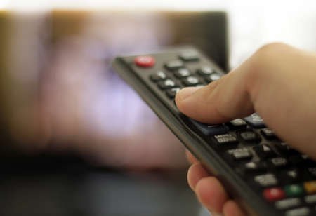 A closeup shot of a man holding a black remote control