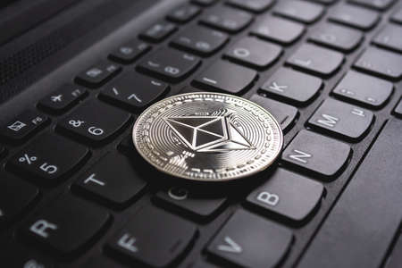 A large coin placed on top of a black computer keyboard
