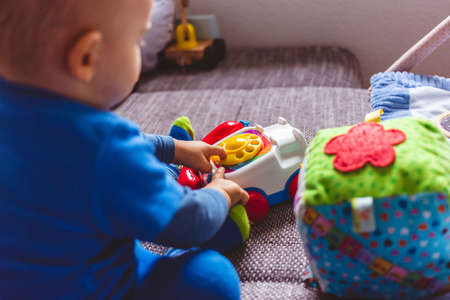 A baby in blue tights playing with his toys on the couchの写真素材