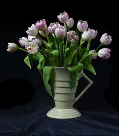A bunch of tulips in an art deco vase with black backgroundの写真素材