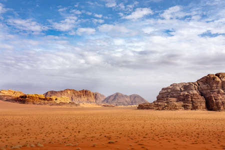 Several cliffs and caves on a desert full of dry grass under a cloudy sky during daytime