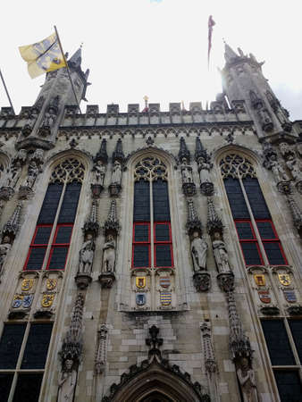 A vertical picture of the Bruges City Hall under a cloudy sky in Belgiumの写真素材