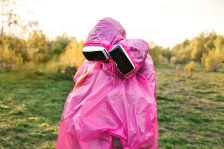 A closeup shot of two people hugging each other in pink plastic raincoats and VR headsets