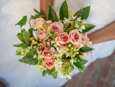 A closeup of a bride holding a bouquet under the lights with a blurry backgroundの写真素材