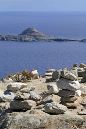 A vertical shot of several stones balanced on top of each other in front of the water