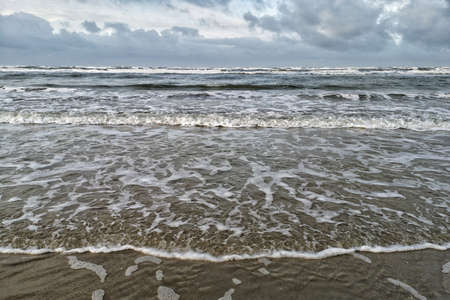 Calm waters of the ocean under a sky full of cloudsの写真素材