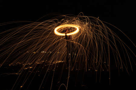 A glowing light extending its sparks into the air as it is rapidly spinningの写真素材