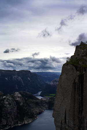 A beautiful scenery of the famous Preikestolen cliffs near a lake under a cloudy sky in Stavanger,...