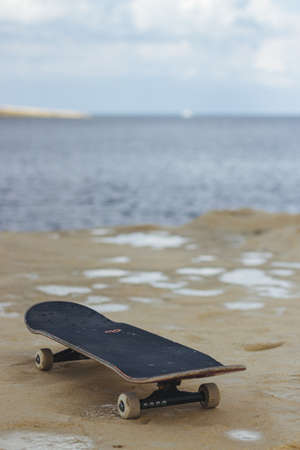 A closeup shot of a black skateboard on the wet sand