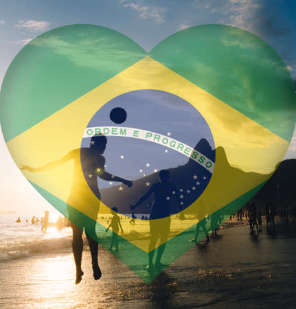 A beautiful image of people playing football at the beach with the flag of Brazil in the shape of a heartの写真素材
