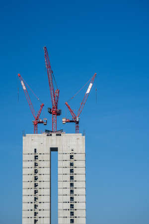 A vertical shot of three red metal constructions on top of a building under a blue sky