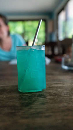 A closeup of the Blue Hawaii cocktail on a wooden table in a bar in Utila