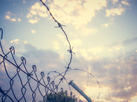 A low angle shot of barbed wire under a cloudy skyの写真素材