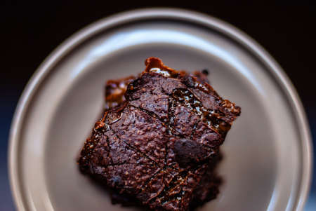 A high angle view of a Chocolate brownie on a plate under the lights with a blurry backgroundの写真素材