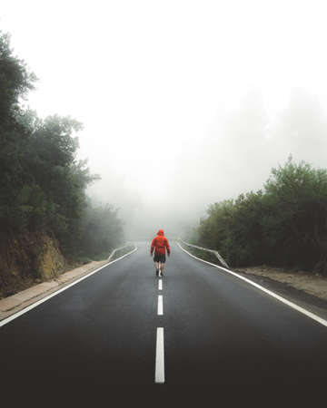 A vertical shot of a male walking through the highway covered by fog - leave everything behind conceptの写真素材