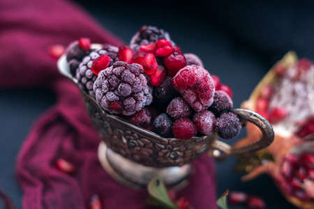 A fresh mix of colorful berries and pomegranate seeds in a metal mug