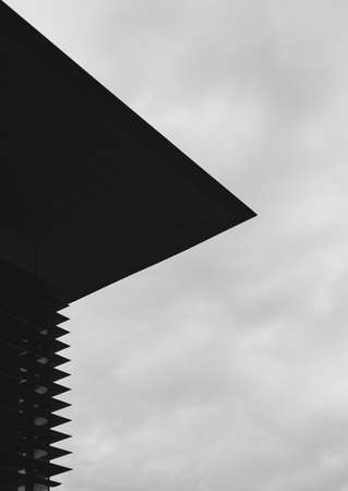 A grey-scale shot of the roof of a modern building with the sky in the backgroundの写真素材