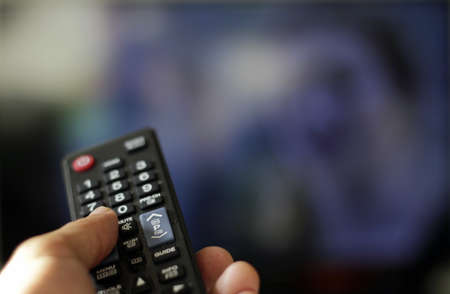 A selective focus shot of a person holding a television remote
