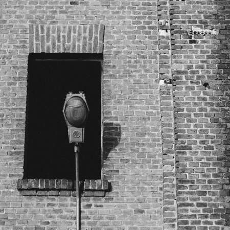 A grey-scale shot of a street lamp in front of an old building with a broken windowの写真素材