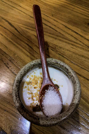 A top view shot of Xinjiang style Yogurt milk with additives in a ceramic bowl with wooden ladleの写真素材