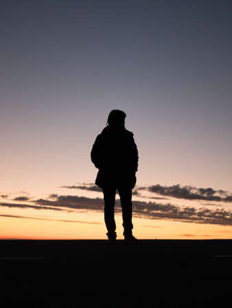 A silhouette of a lonely person enjoying the beautiful view of the sunset