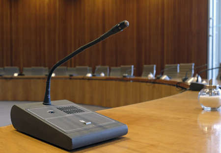 A closeup shot of a goose neck microphone on a conference table
