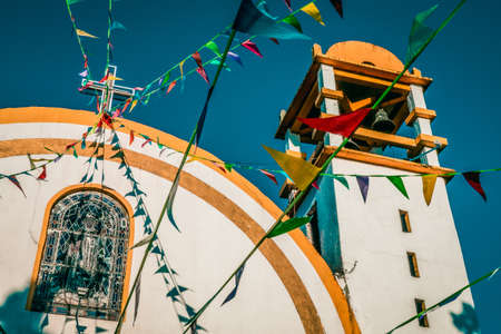 A low angle shot of a white building with a colorful roof under a cloudy skyの写真素材