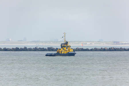 ROTTERDAM, NETHERLANDS - Jun 03, 2014: A tug boat from the port of Rotterdam with the coast line in...
