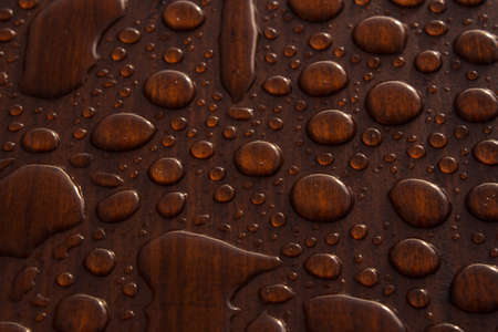 A closeup shot of drips of water on a wooden surfaceの写真素材