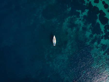 A single boat in the middle of clear blue seaの写真素材